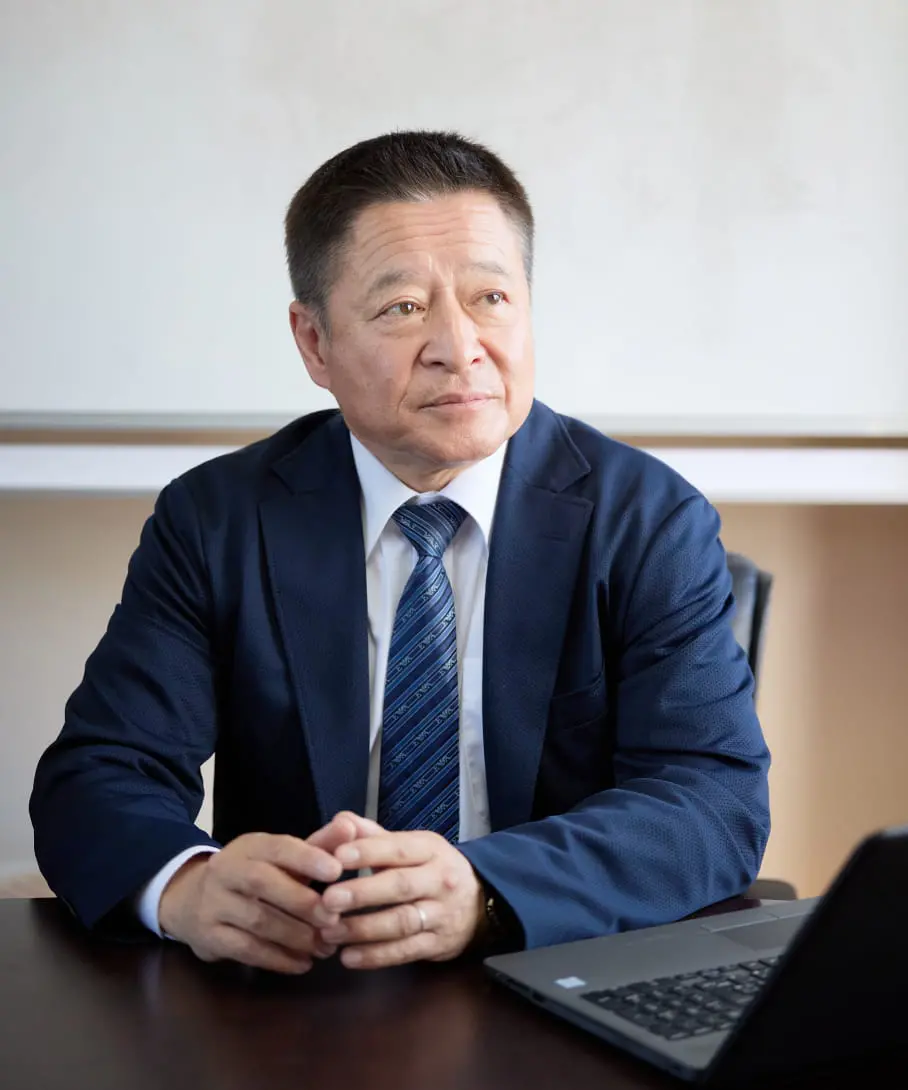 会議室でノートパソコンの前に座り、前を見つめているビジネススーツを着た中年男性